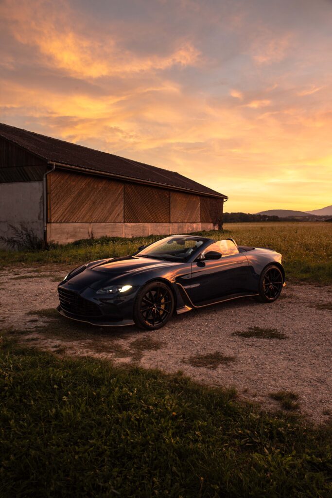 Shooting photo photographe pro suisse Nyon Aston Martin Vantage roaster v12 sous un couché de soleil, dans un pré